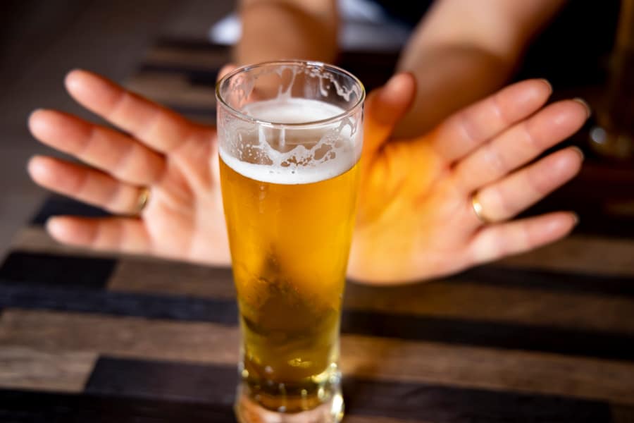 hands shoving away non-alcoholic beer